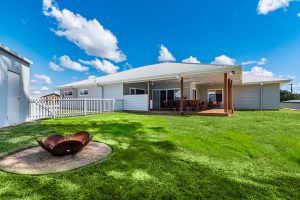 Modern contemporary home exterior with illuminated entry and landscaped front yard.